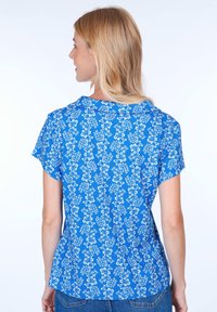 Blue floral short-sleeve blouse with a relaxed fit, featuring a subtle pattern of white flowers and a rounded neckline. Textured fabric.