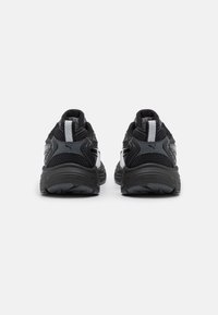 Black athletic shoes with mesh and synthetic upper, rounded heel, reflective accents, and textured outsole for traction.
