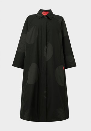 Pitkä musta takki, jossa on hillityt isot tummat pallokuvioinnit, leveät hihat, piilotettu etusuljenta ja kaulus, jossa on punainen sisätunniste.