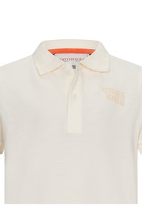 Polo shirt crema realizzato in cotone testurizzato, con colletto classico, tre bottoni e logo ricamato "RETOUR JEANS" in beige chiaro.