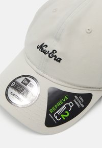 Beige Baseballcap aus 100% recyceltem Stoff. Mit schwarzem gesticktem "New Era"-Logo, verstellbarem Riemen und runden Branding-Aufklebern.