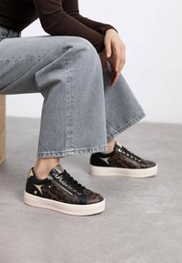 Zapatillas de leopardos en negro y marrón con suela de plataforma, acentos dorados y cordones. Material de cuero texturizado, con detalle de cremallera lateral.