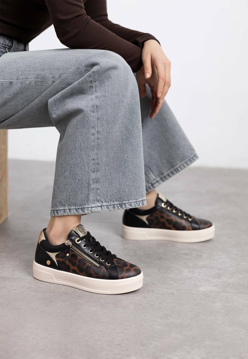 Zapatillas de leopardos en negro y marrón con suela de plataforma, acentos dorados y cordones. Material de cuero texturizado, con detalle de cremallera lateral.