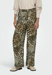 Pantaloni a gamba larga in stampa leopardata con vita elastica, realizzati in un tessuto morbido nelle tonalità di beige e marrone, abbinati a scarpe di colore chiaro.