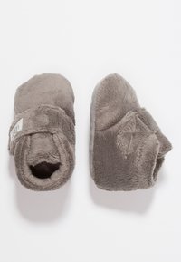 Grijze babyslippers van zacht, gestructureerd materiaal met een vachtachtige uitstraling, voorzien van een klittenbandsluiting en gladde zolen.