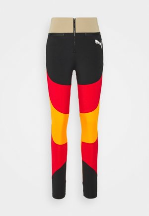 Vysoké sportovní legíny s kombinací černé, červené, žluté a oranžové barvy. Hlavními rysy jsou pás s zipem a strukturovaná látka.