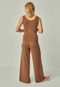 Braunes, geripptes Tanktop und weite Hose aus weichem Strickmaterial. Das Outfit zeichnet sich durch eine lässige Silhouette und minimale Nähte aus.