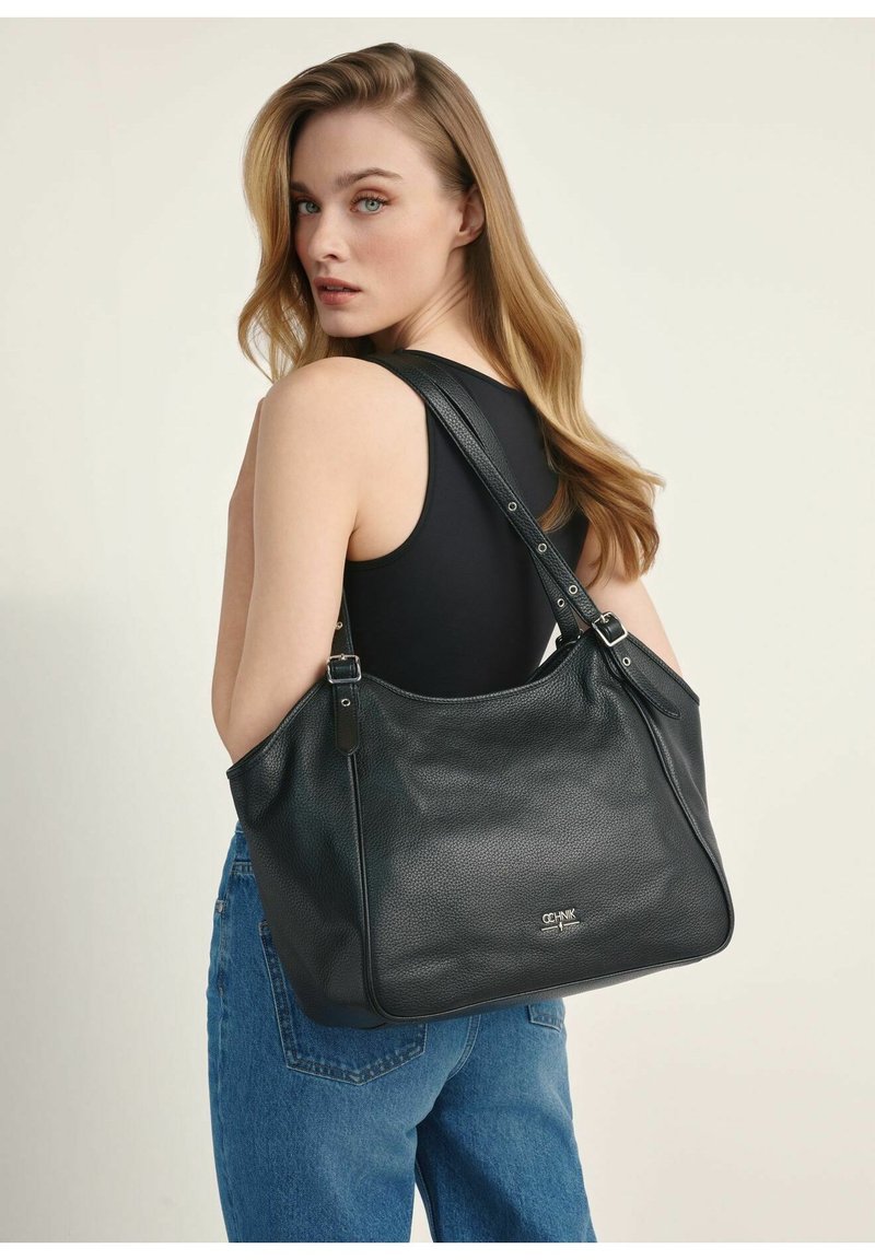 Czarna skórzana torba na ramię o teksturowanym wykończeniu, z dwoma regulowanymi paskami i srebrnymi akcentami logo na dole.