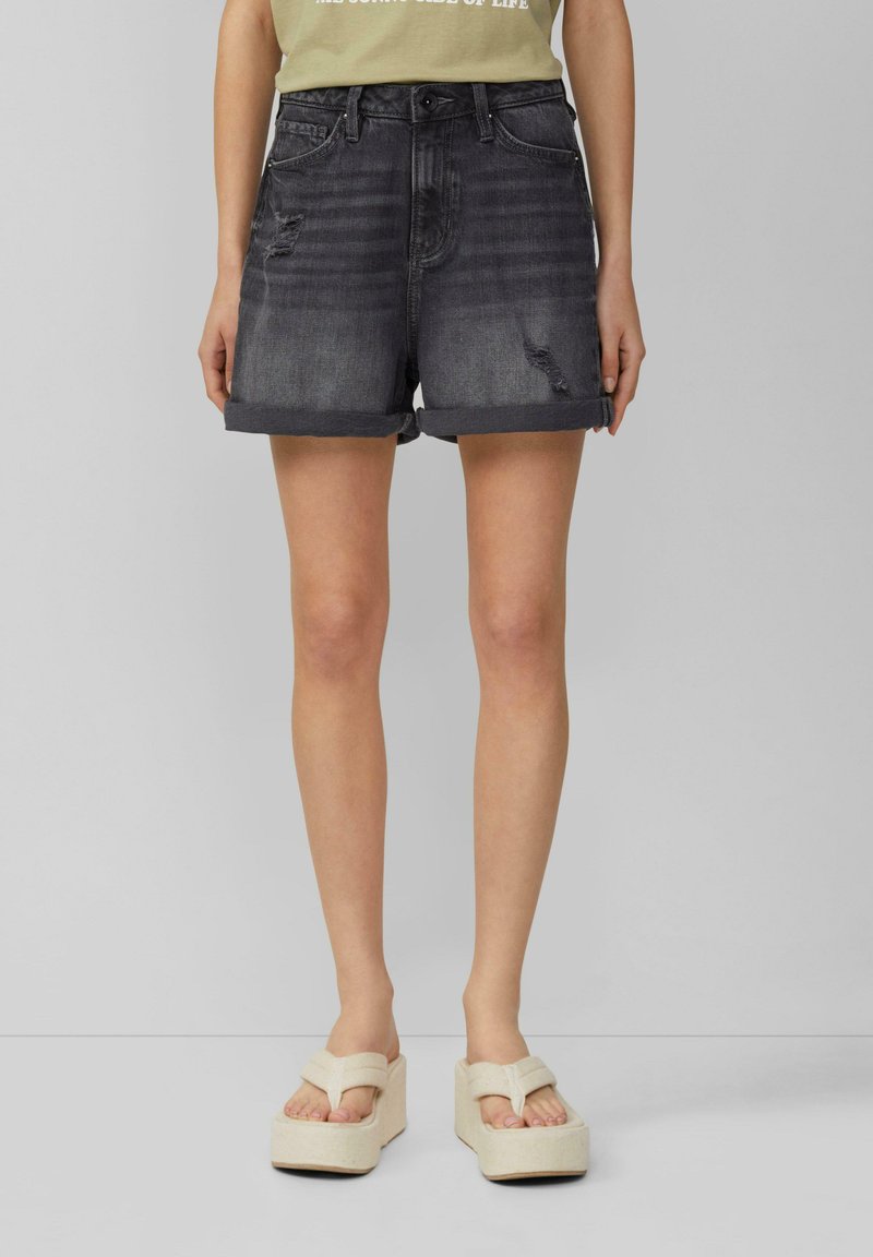 Shorts en denim noir avec un design déchiré, ourlets retroussés et style à cinq poches. Associés à des sandales à plateforme beiges et épaisses.