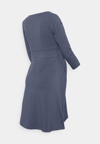 Vestido de mangas longas azul-marinho feito de um tecido suave. Apresenta um corpete ajustado, saia rodada e costuras laterais discretas. Decote redondo.