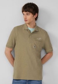 Olivovo zelená polo košeľa, krátke rukávy, štruktúrovaná tkanina, tri gombíky, ľavé predné vrecko s logom a vyšívaným detailom dizajnu.