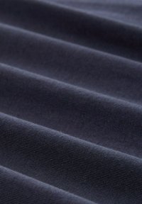 Tissu bleu marine foncé avec une texture côtelée et des plis parallèles courant horizontalement sur la surface, mettant en valeur la profondeur et le détail du matériau.