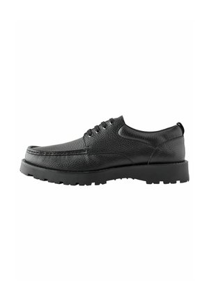 Zapato de cuero negro con superficie texturizada, punta redonda y diseño de cordones. Presenta una suela de goma gruesa con un patrón de banda de rodadura para mayor agarre.
