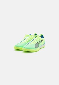 Scarpe da atletica verde brillante con tomaia in rete, dettagli fluorescenti e suola in gomma testurizzata. Presentano un design elegante e dettagli blu a contrasto.
