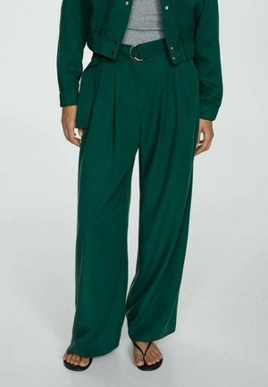 High-waisted wide-leg green pants with pleats and a matching belt, worn with a grey top and black flip-flop sandals.