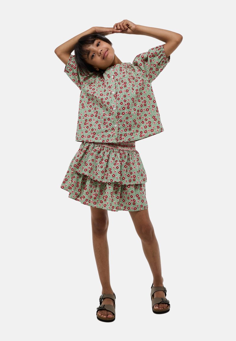 Ensemble deux pièces à imprimé floral comprenant un haut à manches courtes et une jupe à volants en vert, rouge et blanc, fabriqué en tissu léger.