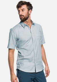 Lichtblauw kortemouwen knoopshirt met een subtiel verticaal streeppatroon, omgeslagen kraag en een borstzakje. Geweven stof.