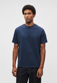 Tumši zils īsroku T-krekls no kokvilnas ar apaļu kaklu un smalku izšuvumu uz krūtīm. Audums ar faktūru.