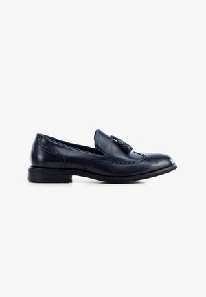 Mocasines de cuero negro con un acabado suave, que presentan perforaciones decorativas y acentos de borlas, sobre un tacón bajo y apilado.
