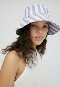 Paarse en witte gestreepte bucket hat met een brede rand, gemaakt van lichtgewicht stof, met een zachte textuur en een casual ontwerp.