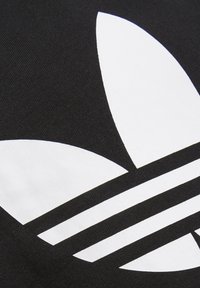 Črno blago z velikim belim cvetličnim logotipom in tremi vodoravnimi črtami spodaj, kar poudarja gladko teksturo in močan kontrast.