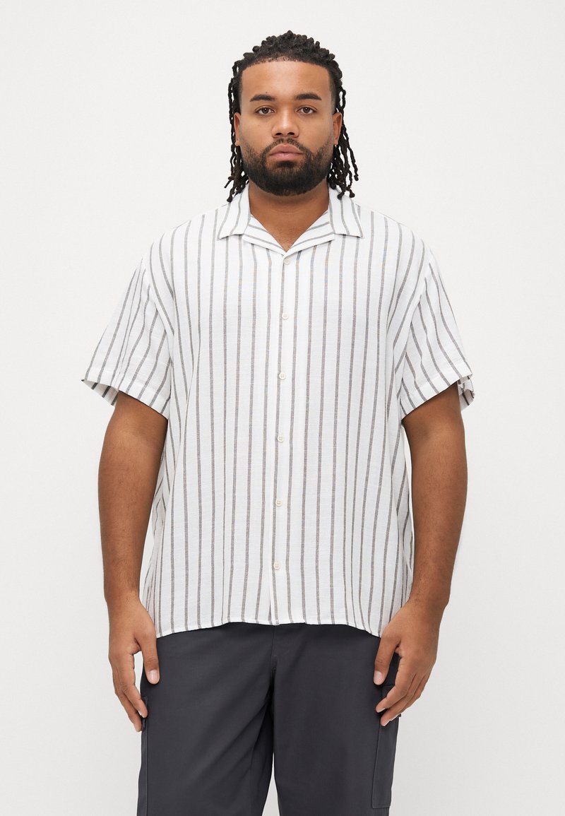 Πουκάμισο με κοντά μανίκια σε λευκό χρώμα με γκρι ρίγες, διαθέτει κουμπιά στο μπροστινό μέρος και άνετη γραμμή. Το ύφασμα φαίνεται ελαφρύ με ελαφρώς υφή ύφανσης.