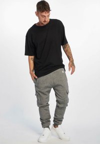 Black oversized t-shirt with short sleeves paired with gray sweatpants featuring side pockets, finished with white sneakers.