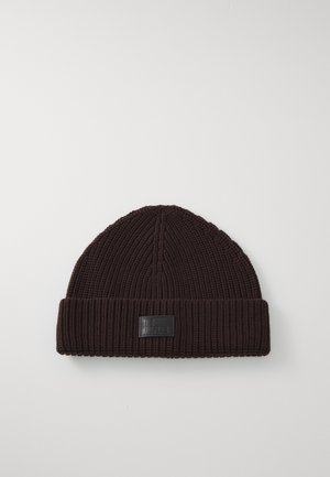Berretto di maglia marrone con una texture a costine, dotato di un risvolto e un'etichetta rettangolare in tessuto nero sul davanti.