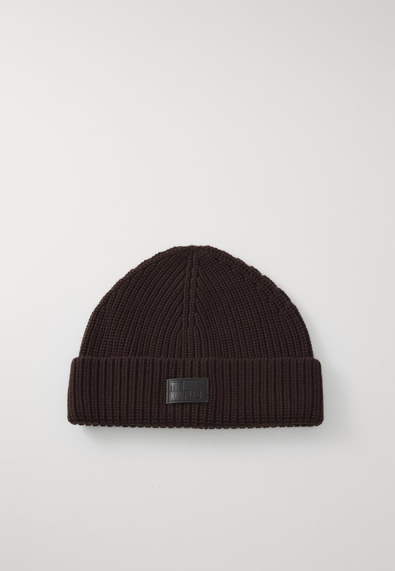 Brūns adīts beanie ar ribota raksta tekstūru, ar salocītu aproci un taisnstūra melnu auduma etiķeti priekšpusē.