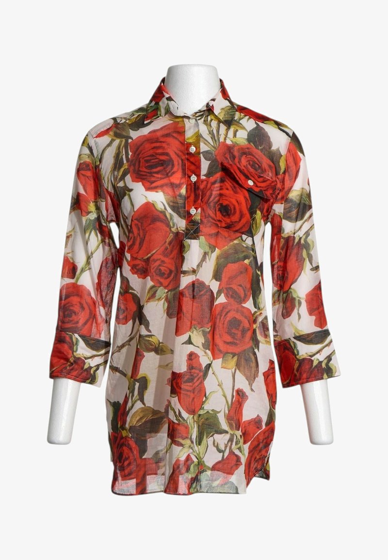 Chemise longue transparente boutonnée avec manches trois-quarts ornée de grandes impressions de roses rouges et de feuilles vertes.