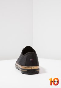 Schwarzer Leinenschuh mit flachem Absatz, hellbraunem Gummisohle und logodetail auf der Rückseite. Minimalistisches Design mit glatter Textur.