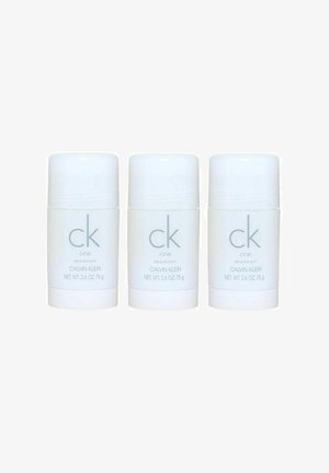 Tre hvide stiftdeodorant med en glat overflade. Hver har "ck one" og "CALVIN KLEIN" trykt i lys grå. Nettovægt 2,6 oz (75 g).