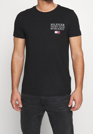 Zwart T-shirt met korte mouwen met de tekst "Hilfiger Yacht Club MCMLXXXV" en een klein rood-wit-blauw rechthoekig logo op de linkerborst.