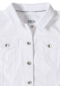 Veste blanche boutonnée avec col, deux poches poitrine et boutons-pression argentés, étiquette "Cecil" à l'intérieur du col.