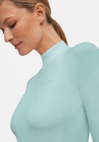 Lichtblauw sporttop met hoge hals, geribbelde schouderaccenten, een gladde textuur en een subtiele logo-opdruk aan de voorkant.