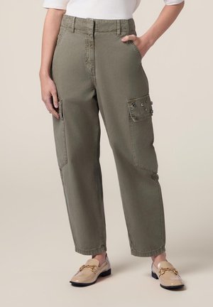 Pantaloni cargo verde oliva con tasche laterali, dettagli in bottone, una vestibilità ampia e un alto giro vita. Abbinati a mocassini beige con una catena dorata.
