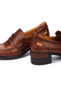 Mocassins en cuir brun avec un motif crocodile à l'avant, des détails de couture, et un talon en bois, avec un logo Pikolinos sur le côté.