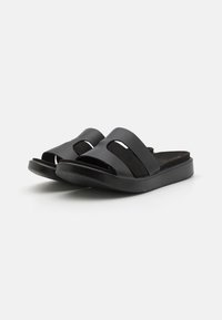 Zwarte slip-on sandalen met dubbele brede banden met uitsparingen, een gestructureerde voetbed en een platte rubberen zool. Eenvoudig en modern ontwerp.
