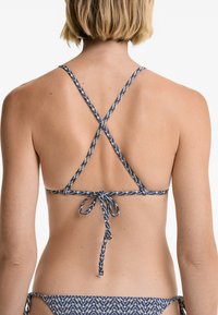 Sötétkék bikini felső geometrikus mintával, állítható keresztpántokkal a hátrészén, és megkötős záródással. Simább textúra és egyszerű dizájn.