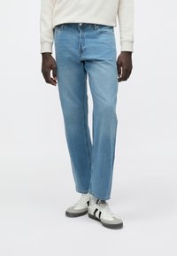 Ανοιχτό μπλε τζιν με χαλαρή εφαρμογή, κλείσιμο με κουμπί και φερμουάρ, και παραδοσιακό σχέδιο με πέντε τσέπες. Υφή με λίγο ξεθώριασμα.