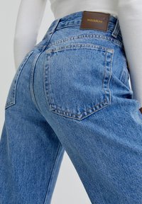 Jeans in denim blu con vita alta, caratterizzati da un'etichetta in pelle Pull&Bear, tasche posteriori e una vestibilità rilassata. Tessuto leggero con una leggera scoloritura.