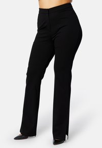 Zwarte, fitted broek met een hoge taille, met een subtiele split aan de zoom. Gemaakt van een zachte, stretchstof voor comfort en flexibiliteit.