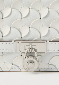 Hvid læderhåndtaske med cirkulært mønster, sølvfarvet lås og logolåsdetalje. Kompakt med glat tekstur og struktureret design.
