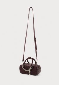 Pequena bolsa tiracolo castanho-escura com frente texturizada, detalhe em corrente prateada, alças duplas e alça de ombro longa e ajustável, em fundo branco liso.