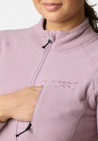 Giacca in fleece rosa chiaro con colletto alto, tasca con zip sul petto e logo ricamato "SWEDEMOUNT". Tessuto liscio, design aderente.