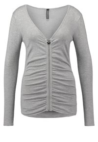 Haut pour femme à manches longues gris clair avec décolleté en V profond et fermeture éclair frontale, détails de tissu froncé le long de la ligne de la fermeture éclair.