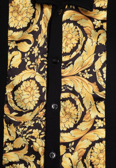 Black button-up shirt featuring a yellow floral and leaf pattern on the front, with smooth fabric and contrasting black sleeves.