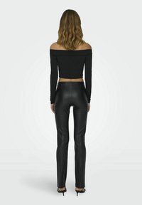 Černý top bez ramínek s dlouhými rukávy, zkrácený, kombinovaný s černými vysokými kalhotami z umělé kůže. Elegantní design a těsný střih.