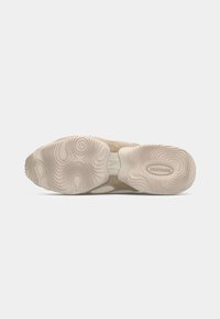 Sola de sapatilhas bege com ondas e padrões texturizados, apresentando um suporte central para o arco e um logótipo proeminente. Material de borracha, design durável.