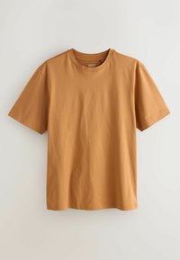 Īsās piedurknes krekliņš ar apaļu kakla izgriezumu siltā, zemes brūnā krāsā. Izgatavots no gludas kokvilnas, ar brīvu piegriezumu un minimāliem šuvju akcentiem.